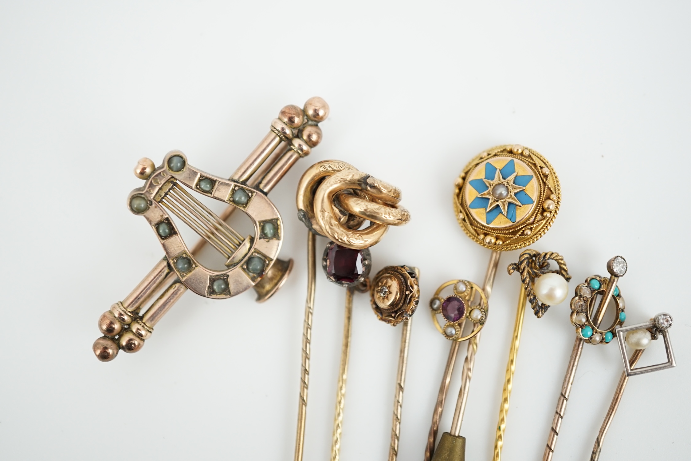 A Victorian yellow metal and cat's eye chrysoberyl set lyre bar brooch, 51mm and eight assorted gem set yellow metal stick pins including enamel and diamond set.